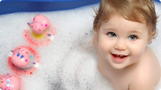 ребенок принимает ванну с резиновыми игрушками